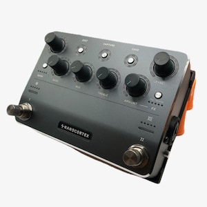 May include: A gray Nanocortex guitar effects pedal with multiple knobs, buttons, and foot switches. The pedal has text that reads "EXIT", "CAPTURE", "SAVE", "LEVEL", "BANK", "BASS", "MID", "TREBLE", "AMOUNT", "FX", and "NANOCORTEX".