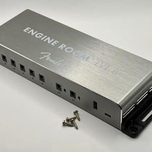 May include: A silver Fender Engine Room LVL 8 power supply unit with a brushed metal finish. The device features multiple circular power ports, a USB port, and a side-mounted mounting bracket. Four small metal screws are placed in front of the unit.