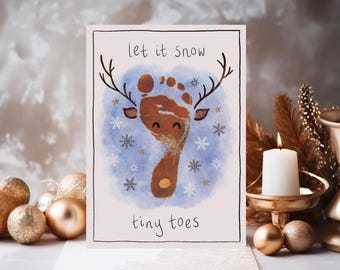 May include: A greeting card with a reindeer footprint design. The card features a brown footprint with antlers, snowflakes, and the text "let it snow tiny toes". The background has a blue watercolor effect.