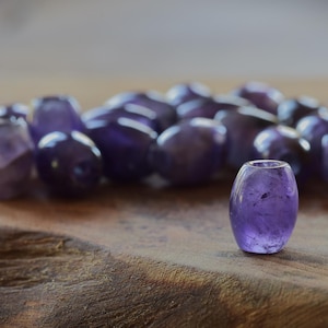 Könnte beinhalten: Nahaufnahme einer Gruppe von Amethyst-Edelsteinkugeln, wobei eine Kugel im Fokus steht. Die Kugeln sind tiefviolett und haben eine glatte, polierte Oberfläche.
