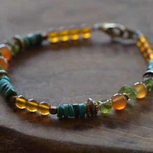 Könnte beinhalten: Ein mehrfarbiges Perlenarmband mit orangefarbenen, grünen und blauen Perlen. Das Armband hat einen silbernen Verschluss.