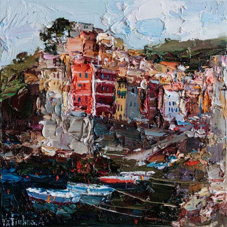 May include: Impasto oil painting depicting a coastal village with vibrant buildings and boats. The artwork uses thick brushstrokes to create texture. Buildings are painted in red, orange, and white, set against a blue sky and green hills.