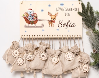 May include: Wooden advent calendar with a decorative illustration of a deer and animals in a sleigh. The calendar has small beige fabric bags numbered 1-24 hanging below. The text "Adventskalender von Sofia" is printed on the wooden board.