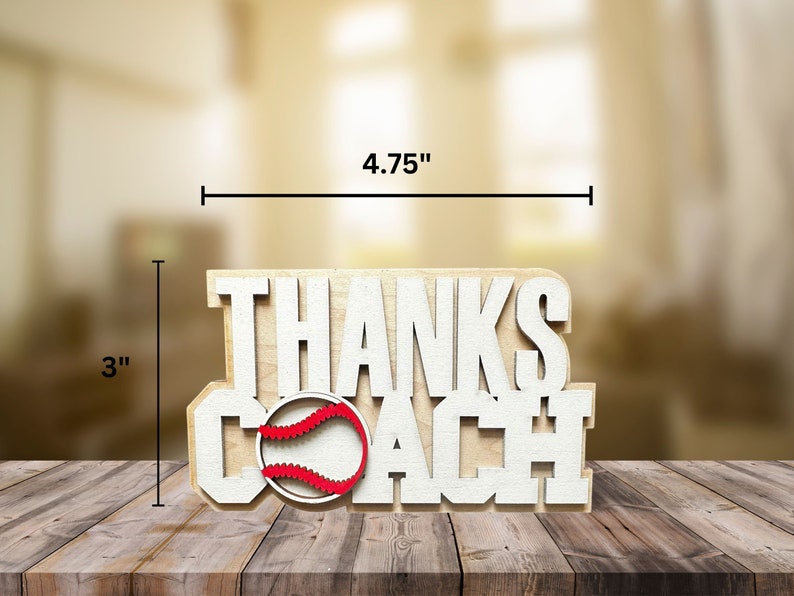 Puede incluir: Se&ntilde;al de madera con las palabras "Thanks Coach" en letras blancas. Una pelota de b&eacute;isbol roja y blanca est&aacute; en el medio de la se&ntilde;al. La se&ntilde;al mide 12,1 cm de ancho y 7,6 cm de alto.