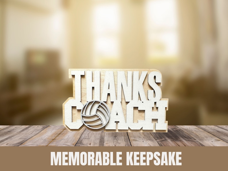 May include: A wooden volleyball coach appreciation gift. The words "THANKS COACH" are cut out in white, with a volleyball graphic. The words "MEMORABLE KEEPSAKE" are printed below the gift. The gift is displayed on a wooden surface.
