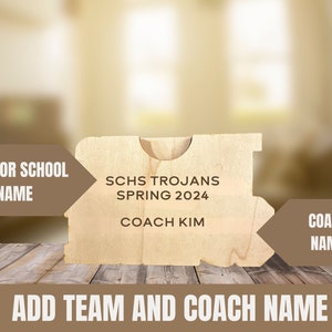 Puede incluir: Una placa de madera con el texto "SCHS TROJANS SPRING 2024 COACH KIM" y espacios en blanco para "TEAM OR SCHOOL NAME" y "COACH NAME".