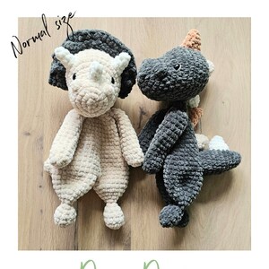 Könnte beinhalten: Zwei gehäkelte Dinosaurierspielzeuge, eines beige und eines grau, mit dem Text "Dino Doris Crochet pattern / haakpatroon" darunter.