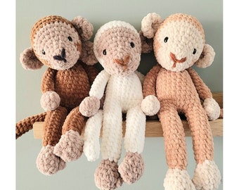 May include: Three crocheted monkey plushies, one brown, one white, and one beige, sitting on a wooden shelf. The crochet pattern is called "Monkey Axel / Aapje Axel" and is available in English and Dutch.