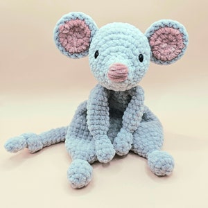 May include: A soft, gray crocheted mouse toy with pink ears and a pink nose. The mouse is sitting with its legs crossed and its arms folded.
