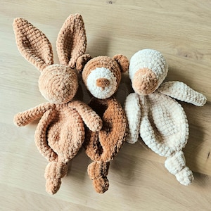 Op de afbeelding: Drie gehaakte knuffels: een bruin konijn, een bruine beer en een crèmekleurige beer. Het konijn heeft lange oren en een pluche staart. De beren hebben kleine, ronde oren en knoopjesogen.
