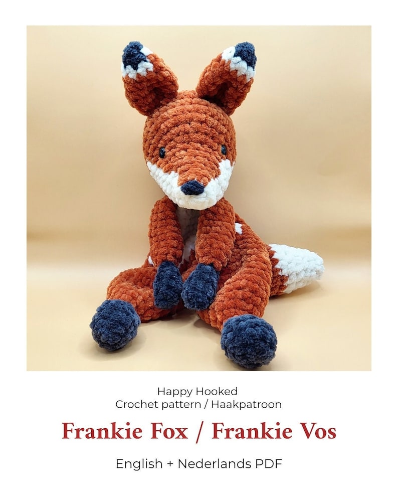 May include: A crocheted fox amigurumi toy with orange, white, and blue yarn. The toy is sitting on a light brown surface. The text "Happy Hooked Crochet pattern / Haakpatroon Frankie Fox / Frankie Vos English + Nederlands PDF" is below the toy.
