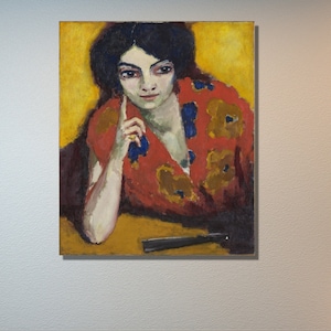 Puede incluir: Una pintura de una mujer con cabello oscuro y una blusa con estampado rojo y dorado. Ella está mirando al espectador con una expresión pensativa. El fondo es de color amarillo.