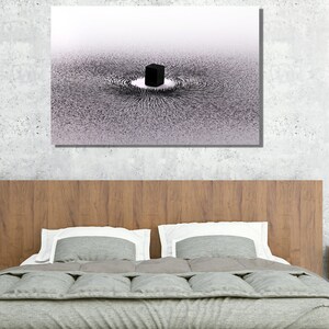 May include: A black and white abstract art print of a cube surrounded by a swirling pattern of lines. The print is framed and hanging on a wall above a bed.