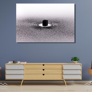 May include: A black and white abstract art print featuring a black cube in the center of a swirling pattern. The print is framed and hanging on a blue wall.