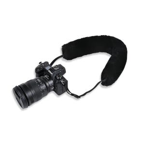 May include: A black Nikon camera with a lens attached, paired with a black, plush camera strap. The strap is designed for comfort and support. The camera is positioned on a white background.
