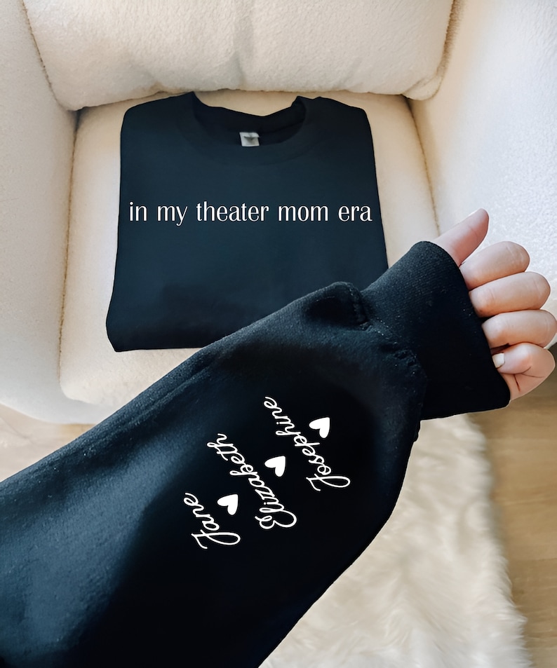 May include: Black sweatshirt with the text "in my theater mom era" on the front and the names "Jane", "Elizabeth", and "Josephine" with hearts on the sleeve.