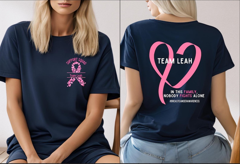 Peut inclure: T-shirt bleu marine avec texte et graphiques roses. Le devant du t-shirt indique "SUPPORT SQUAD" et "Team Leah" avec un motif de ruban rose. Le dos du t-shirt pr&eacute;sente un c&oelig;ur en ruban rose avec "TEAM LEAH" et le texte "IN THIS FAMILY, NOBODY FIGHTS ALONE".
