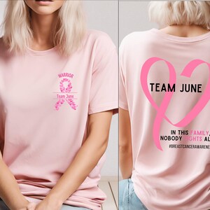 Peut inclure: Un t-shirt rose clair avec les mots "WARRIOR" et "Team June" imprim&eacute;s sur le devant, ainsi qu'un motif de ruban rose. Le dos du t-shirt pr&eacute;sente un grand ruban rose en forme de c&oelig;ur avec les mots "TEAM JUNE" et le message "IN THIS FAMILY, NOBODY FIGHTS ALONE".