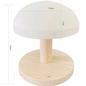 Può includere: Una lampada di legno bianca a forma di fungo con una base di 19 cm di diametro e una parte superiore alta 7 cm. La lampada è alta 16 cm.