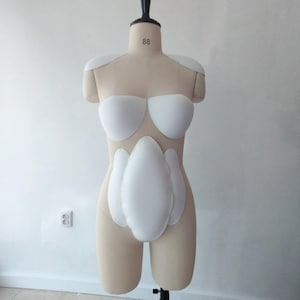 May include: A beige dress form with white padding for the shoulders, bust, and abdomen. The dress form has a black neck piece and is mounted on a metal stand. The number "88" is printed on the neck.