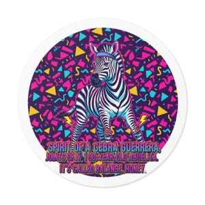May include: A round sticker featuring a zebra with a blue and pink headband, set against a purple background with colorful geometric shapes. The text reads: "SPIRIT OF A CEBRA GUERRERA, JOINTS OF A 100-YEAR-OLD ABUELITA, IT'S CALLED BALANCE, HONEY."