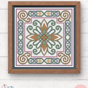 Może przedstawiać: Oprawiona grafika haftu krzyżykowego z symetrycznym wzorem kwiatowym w odcieniach pomarańczu, zieleni i niebieskiego na białym tle. Grafika jest oprawiona w drewnianą ramę z niebieską wewnętrzną obwódką. W prawym dolnym rogu znajduje się napis "PDF".