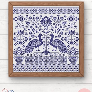 Peut inclure: Une broderie au point de croix encadrée, représentant deux paons face à face, avec un motif central d'arbre. L'œuvre est en nuances de bleu et blanc, avec des éléments floraux et géométriques. Le cadre est en bois. Les textes "Pura Creations" et "PDF" sont visibles.