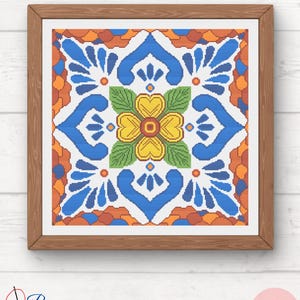 May include: A colorful cross-stitch pattern featuring a stylized flower with blue, yellow, green, orange, and red accents. The pattern is framed in a wooden frame.