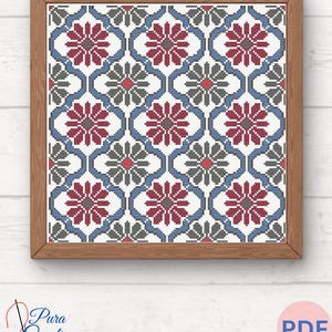 May include: A cross stitch pattern featuring a repeating geometric design with red, blue, and grey flowers. The pattern is framed in a brown wood frame.
