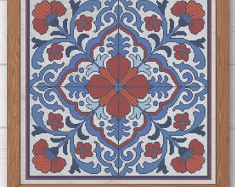 May include: A framed cross-stitch pattern featuring a symmetrical floral design in red, blue, and white. The artwork is enclosed in a wooden frame. The design includes the text "Pura Creations" and "PDF".