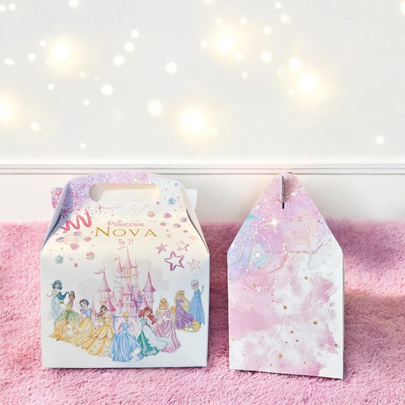 K&ouml;nnte beinhalten: Zwei Party-Geschenkboxen zum Thema Prinzessin. Eine Box ist wei&szlig; mit einem rosa Schloss und mehreren Disney-Prinzessinnen. Die Box hat einen Griff und es steht "Princess Nova is 7" darauf. Die andere Box ist rosa mit einem Aquarelldesign und goldenem Glitzer.