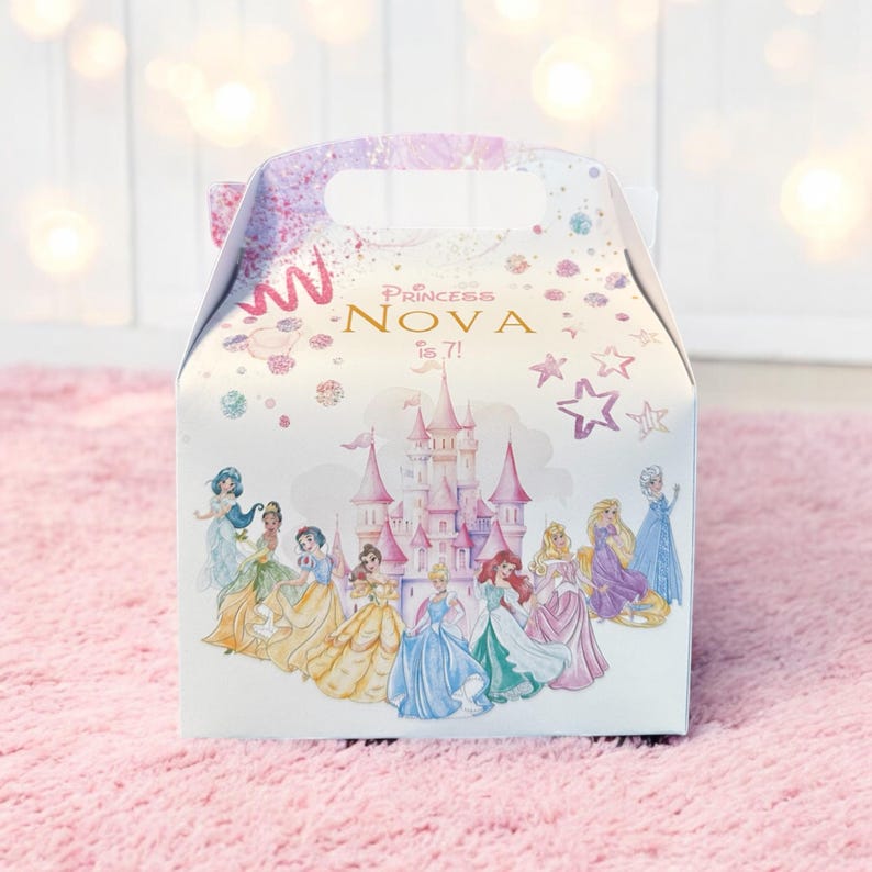K&ouml;nnte beinhalten: Eine wei&szlig;e Geschenkbox mit einem rosa Schloss und Disney-Prinzessinnen. Die Box hat einen Griff und auf der Vorderseite steht "Princess Nova is 7!"