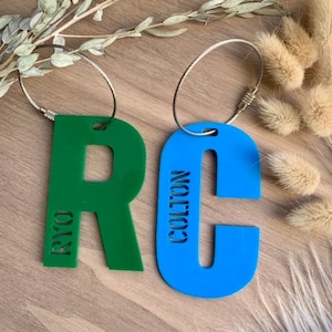 Peut inclure: Deux étiquettes à bagages personnalisées, une verte avec le nom "RYO" et une bleue avec le nom "COLTON".