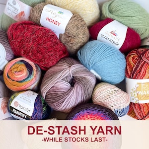 May include: A collection of colorful yarn skeins in various textures and hues, including red, blue, and multicolored options. The image includes labels with brand names like "Honey" and "Harmony." Text at the bottom reads "DE-STASH YARN -WHILE STOCKS LAST-".