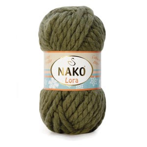 Pode incluir: Uma grande bola de fio Nako Lora verde-oliva. O fio é espesso e volumoso, com uma aparência texturizada. Um rótulo envolve o centro, com o nome da marca e os detalhes do produto. O rótulo tem um design azul claro e dourado.