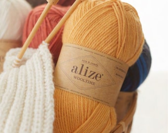 May include: A ball of yellow yarn with the label "alize' Wooltime" and the words "easy & comfy" on it. The yarn is in a basket with other balls of yarn.