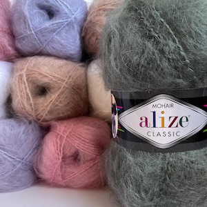May include: A collection of colorful mohair yarn balls in shades of pink, lavender, peach, and green. The yarn is labeled "Alize Classic Mohair". The image shows the soft texture of the yarn, ideal for knitting or crocheting projects.
