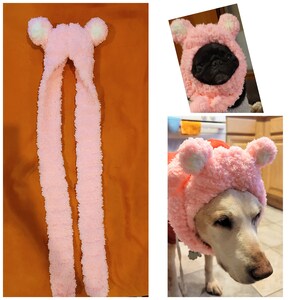 May include: Pink fuzzy bear hat with long scarf for a dog. The hat has white ears and a pink fuzzy texture.