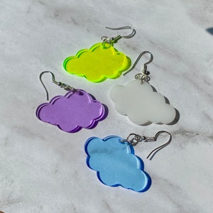 May include: Four pairs of cloud-shaped earrings in different colors. The earrings are made of acrylic and have a silver hook. The colors are neon yellow, purple, white, and light blue.