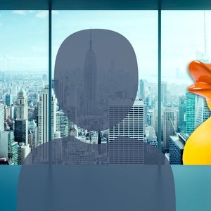 May include: A silhouette of a person looking out a window at a cityscape with a yellow rubber duck in the foreground.