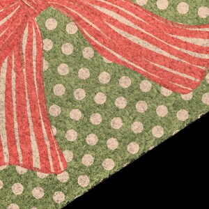 May include: A rectangular doormat with a coarse, fibrous texture featuring a green background covered in a pattern of small, light-coloured polka dots. A large, stylised red bow with white vertical stripes is printed across the top corner.