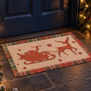 K&ouml;nnte beinhalten: Eine rechteckige Fu&szlig;matte mit naturfarbener Mitte, die eine rote Silhouette des Weihnachtsmanns im Schlitten mit Rentier sowie kleine Schneeflockenmotive zeigt. Die Matte hat einen rot-gr&uuml;n-beigen Karorand an allen vier Seiten.