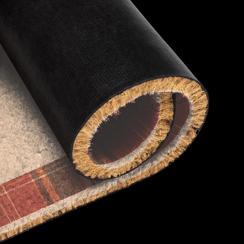 May include: A rolled doormat featuring a textured, natural tan coir surface with a red and brown plaid pattern. The underside of the mat is made of a smooth, solid black material, showing the contrast between the fibrous top and the backing.