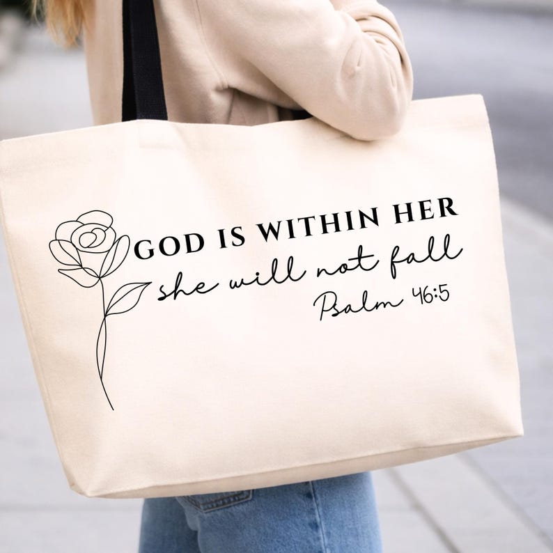 Op de afbeelding: Cr&egrave;mekleurige draagtas met zwarte handvatten. De tas heeft een zwarte lijntekening van een roos en de tekst "GOD IS WITHIN HER she will not fall Psalm 46:5". De tas is gemaakt van stevige stof.
