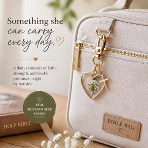 May include: A beige textured Bible bag with a gold-toned zipper and a rectangular label reading BIBLE BAG. A heart-shaped charm containing a pressed flower and a mustard seed hangs from the zipper, accompanied by a small gold cross charm.