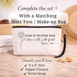 Op de afbeelding: Witte mini-tote bag met zwarte rits en polsband. De tas heeft een bloemenontwerp en de tekst "GOD IS WITHIN HER she will not fall Psalm 46:5". Afmetingen: ongeveer 23 x 15 cm.