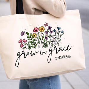 May include: Cream-colored tote bag featuring a colorful floral design with butterflies. The words "grow in grace" are written in a cursive font, with the Bible verse 2 Peter 3:18 below the text. The bag has black straps.