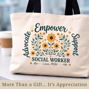 May include: Cream-colored tote bag with black handles. The bag features a floral design with sunflowers and the words "Empower, Advocate, Support, Social Worker" in dark green. The text "Lexie, MSW" is also included.