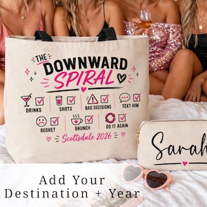 May include: A beige canvas tote bag with black handles and the text "THE DOWNWARD SPIRAL" in black and pink. Below are icons and text including "Drinks", "Shots", "Bad Decisions", and "Text Him". A small cosmetic bag and heart-shaped sunglasses are also visible.