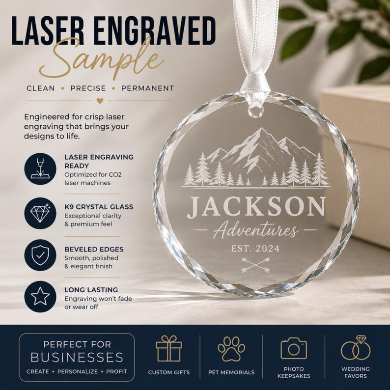 May include: A circular K9 crystal glass ornament with beveled edges, suspended by a white ribbon. The glass features a laser-engraved mountain and pine tree landscape above the text JACKSON Adventures EST. 2024 and two crossed arrows.
